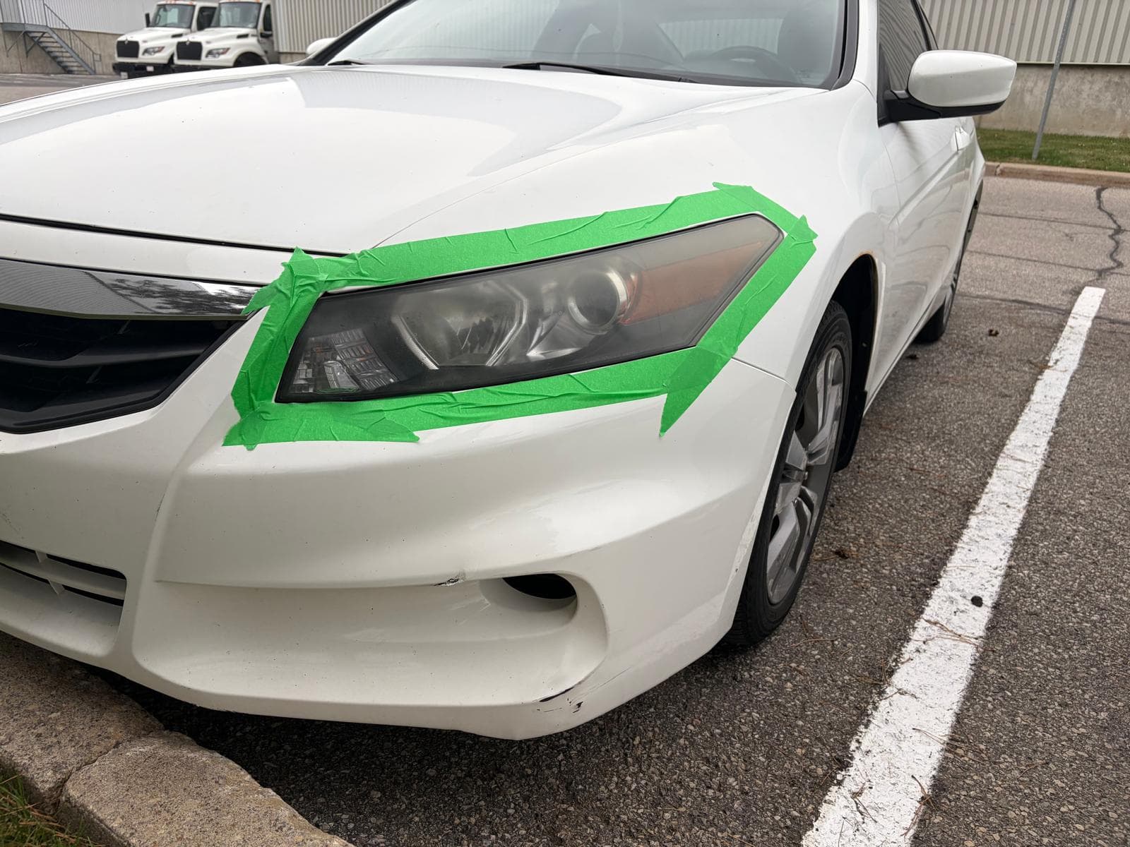 Honda Accord headlight masked off with green painter's tape mid-restoration